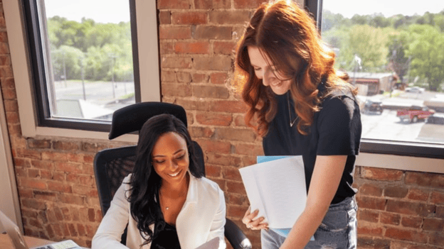 two small business employees smiling and looking at laptop
