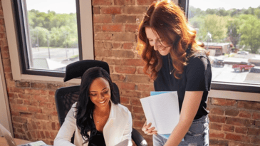 two small business employees smiling and looking at laptop